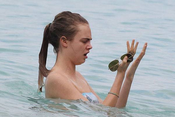 Cara Delevingne is pictured at the beach playing football